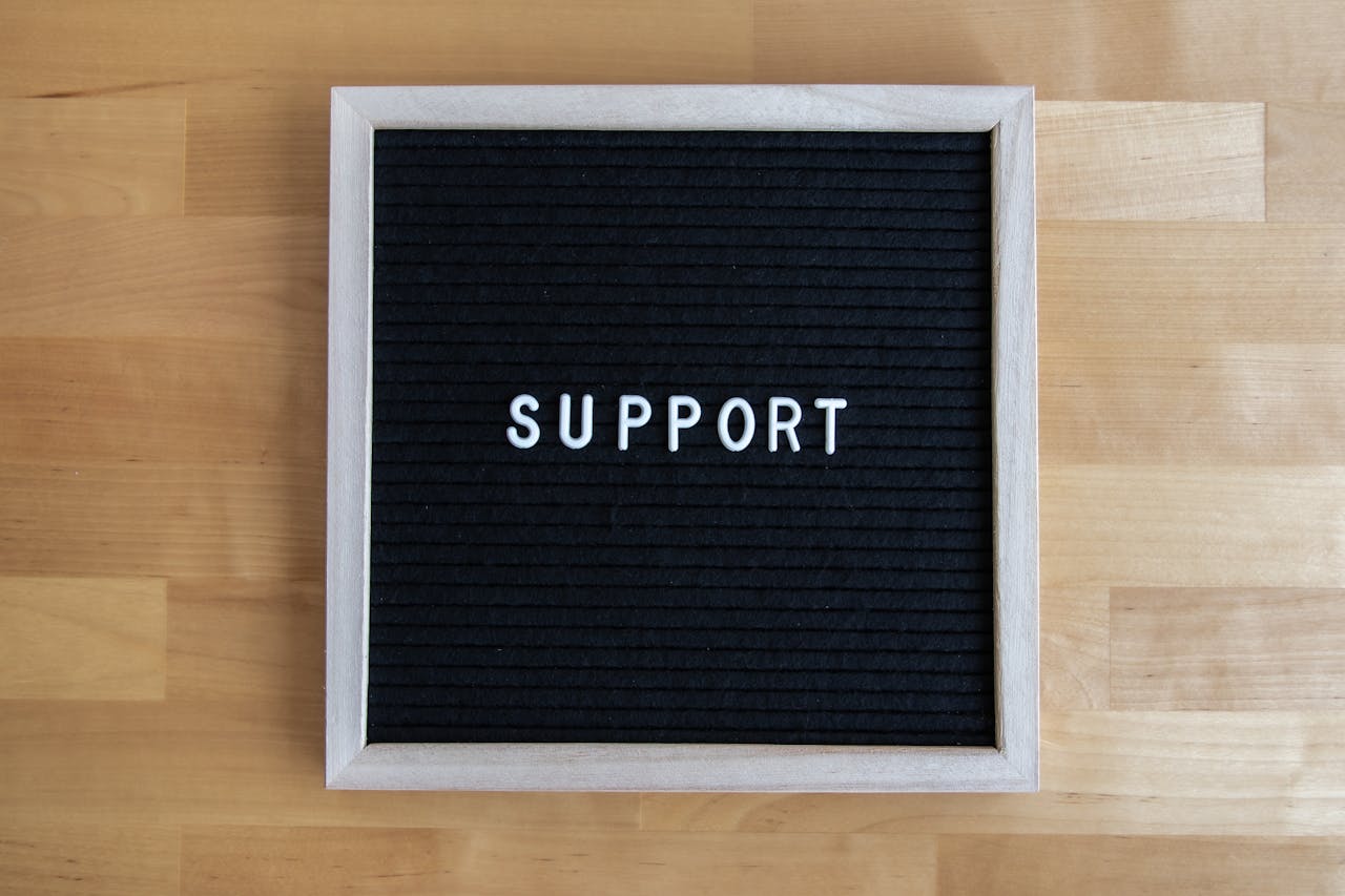 Black letter board displaying the word SUPPORT on a wooden table, offering ample copyspace.